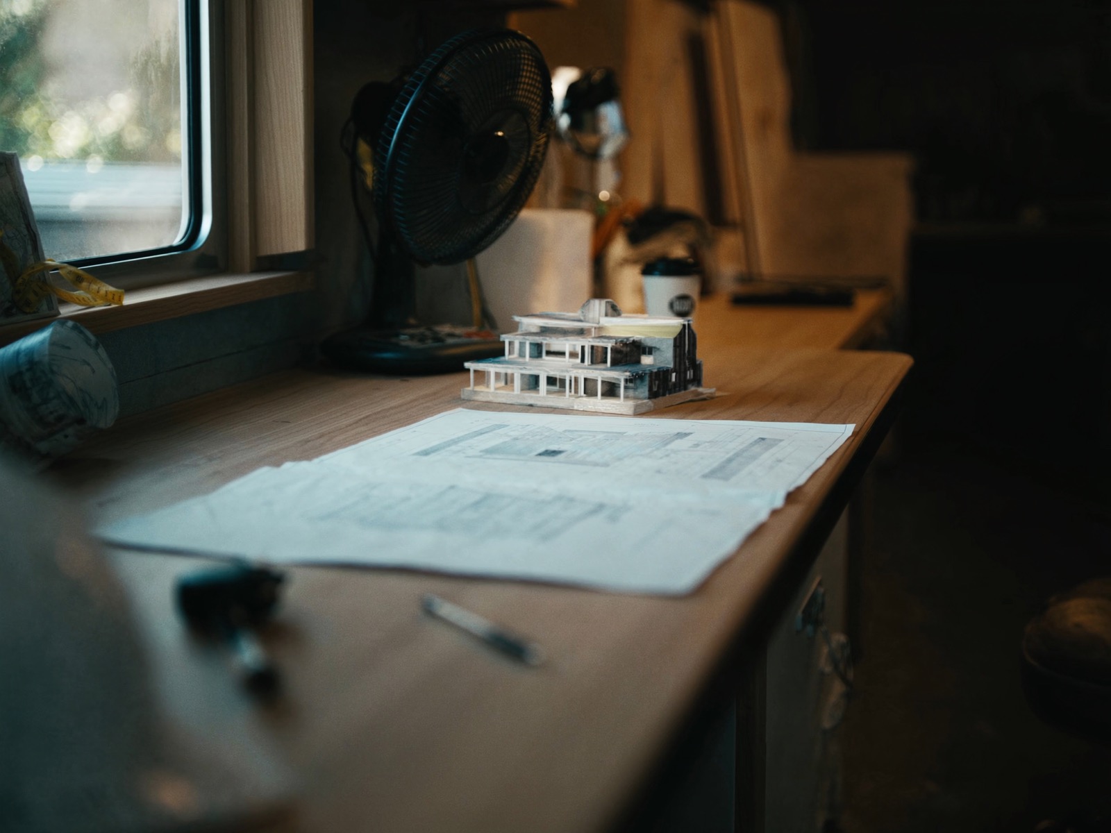 Construction blueprints and a small building model on a drafting table